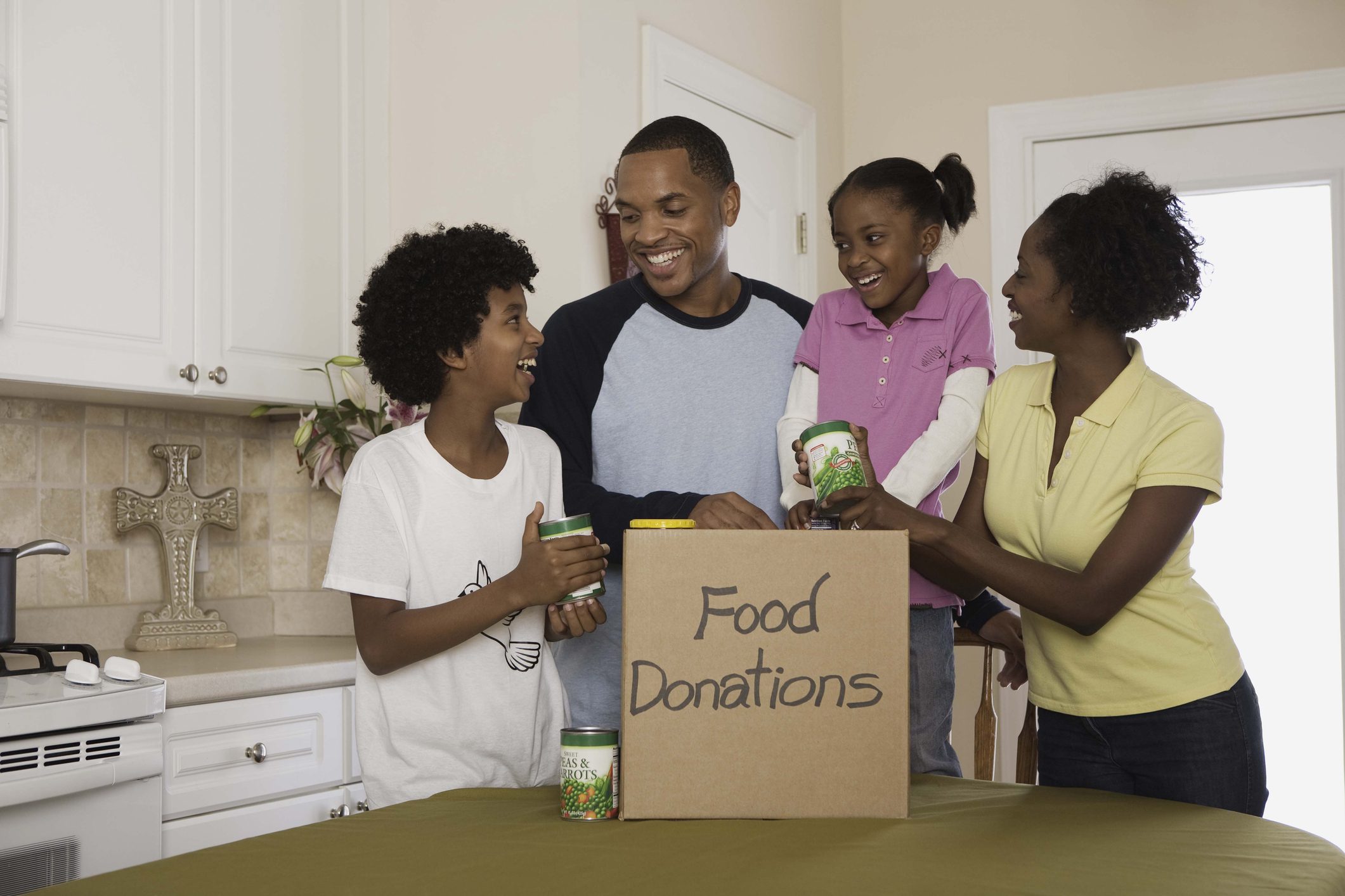 Family putting canned food in donations box indoors