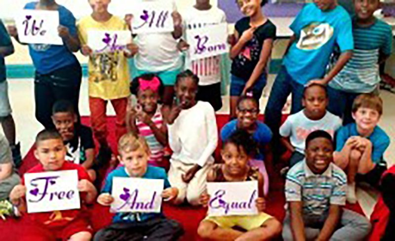 Happy interracial kids smiling while some of them holding a sinage