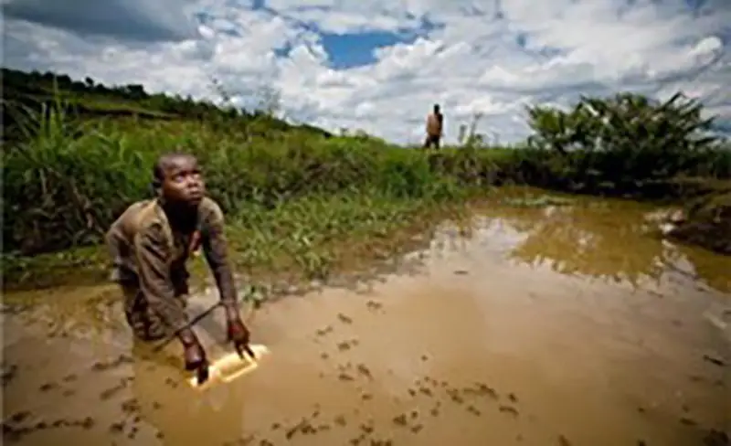 Kid getting water from a dirty lake